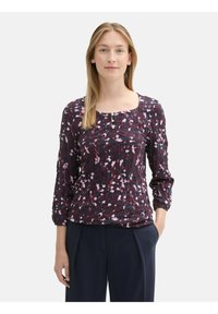 Blusa floreale a maniche lunghe con scollatura quadrata e dettagli a bottoni, su uno sfondo scuro con accenti rosa e bianchi. Tessuto morbido.