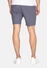 Pantaloni corti grigi da uomo in cotone, con taglio dritto, tasche laterali e finitura orlata, abbinati a sneakers bianche.