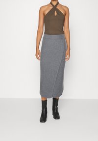 Brun halterneck topp med en nyckelhålsdetalj, som matchas med en grå filtskjol. Slät tyg med en figurnära silhuett, kompletterad med svarta ankelstövlar.