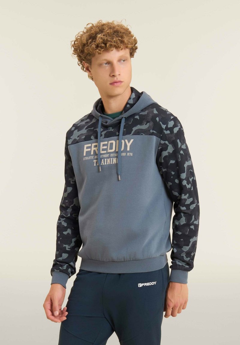 Felpa con cappuccio grigia con maniche a motivo mimetico, logo sul petto e chiusura con coulisse. Tessuto morbido con orlo a coste.