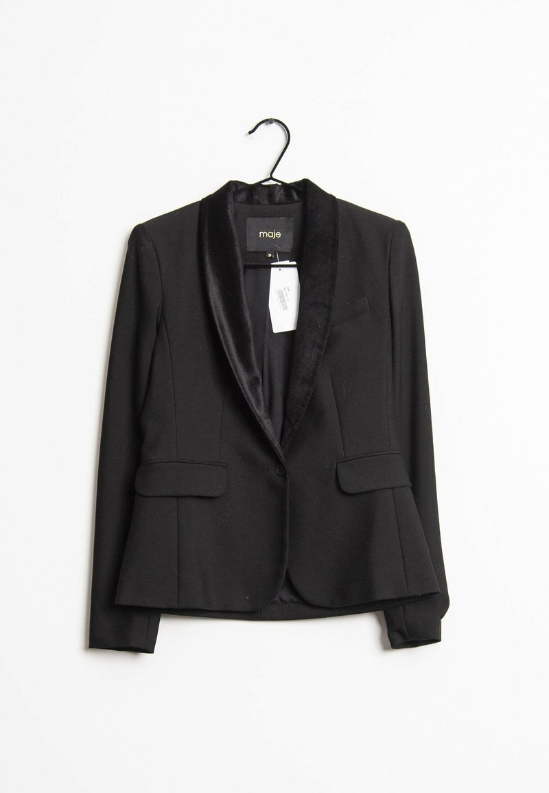 Blazer noir ajusté avec revers en satin suspendu à un cintre noir sur fond blanc, avec poches à rabat à l'avant et étiquette de prix visible.