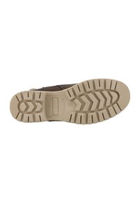 Een brown boot met een getextureerde rubberen zool die diepe groeven heeft en een logo bevat. De zool is lichtbruin met een zigzagpatroon voor grip.