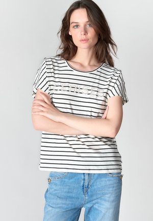 Camiseta de manga corta a rayas en blanco y negro, con un corte relajado y un detalle de texto decorativo en la parte frontal.