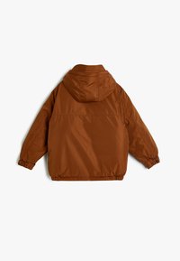 Brun hættejakke lavet af glat nylon, med elastiske manchetter og kant, samt en dropped shoulder design for en afslappet pasform.