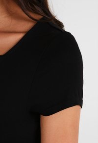 Czarny t-shirt krótki rękaw wykonany z miękkiego, elastycznego materiału z okrągłym dekoltem; charakteryzuje się gładką fakturą i starannym przeszyciem przy rękawach.