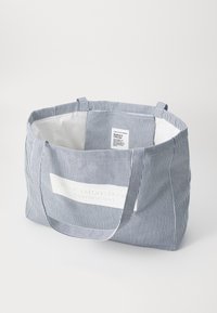 Rutet stoff tote bag med to håndtak. Har en hvit tekstlapp med teksten "WEEKEND OFFENDER" og en glatt hvit innside.