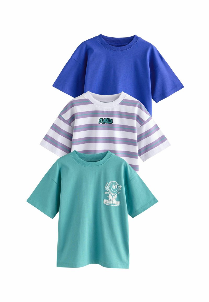 Tres camisetas: una azul sólida, una blanca con rayas moradas y logo, y una verde menta con estampado gráfico. Todas tienen mangas cortas y cuellos redondos.