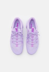 Pár světle fialových sportovních bot Nike Free s uvázanými tkaničkami, síťovaným svrškem a označenými jazýčky, pohled shora na bílém pozadí.