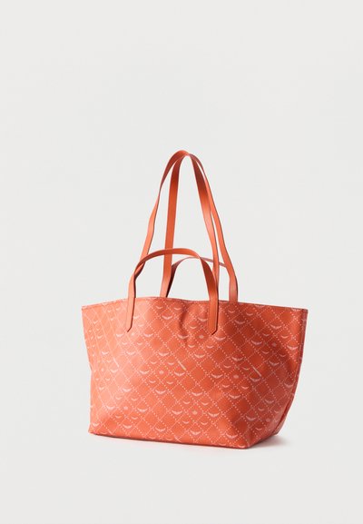 Grand sac cabas corail avec deux séries de poignées en cuir et un motif blanc subtil répétitif sur tissu texturé.