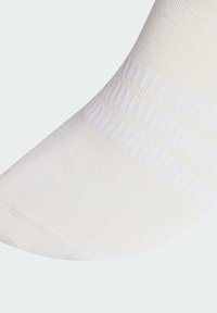 Calcetín blanco con una textura suave, que presenta rayas acanaladas y un diseño de puntera redondeada. El tejido parece ligero y transpirable.