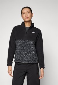 Black fleece pullover with a quarter-zip, featuring a leopard print pattern at the waist. Logo accent on the left chest.