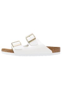 Sandalia blanca con dos correas ajustables, hebillas en tono dorado y plantilla de corcho. Suela blanca texturizada para mayor tracción. Diseñada para la comodidad.