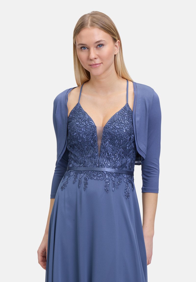 Niebieska sukienka z misternym haftem kwiatowym i głębokim dekoltem w kształcie litery V, w zestawieniu z dopasowanym miękkim kardiganem z rękawami o długości trzech ćwierci.