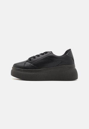 Adidași negri cu un partea superioară netedă, din material sintetic, cu vârf rotund și șase găuri pentru șireturi. Au o talpă groasă, texturată, pentru aderență și suport.