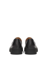 Black leather shoes with a smooth texture, featuring a sturdy black sole and a minimalist design. Back view shows stitching details and rounded heels.