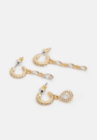 Gold-tone earrings featuring curved frames with clear rhinestones, a chain of decorative links, and a teardrop-shaped crystal accent.