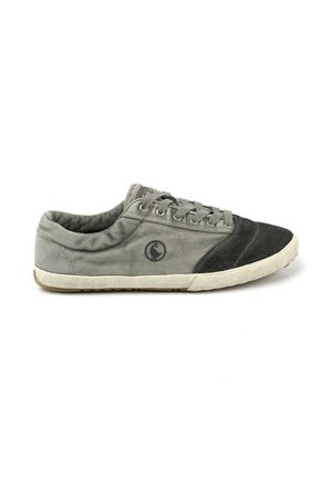 Zapatilla casual de corte bajo con cuerpo de lona gris, puntera de ante negro, cierre con cordones y suela de goma blanca aislada sobre fondo blanco.