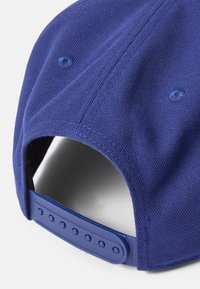 Gorra azul marino con tejido texturizado, cierre snapback y costuras visibles. El interior no está forrado y cuenta con orificios de ventilación.