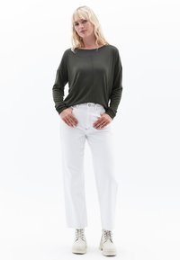 Olijfgroene lange mouw top met een ronde hals, gecombineerd met witte high-waisted rechte broek en crèmekleurige chunky veterschoenen.