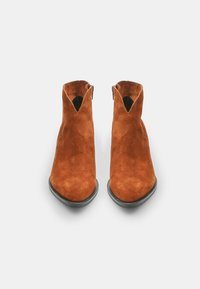 Botas de ante hasta el tobillo en un rico tono naranja-marrón, con puntera puntiaguda, corte en forma de V en la parte delantera y suela de goma negra.