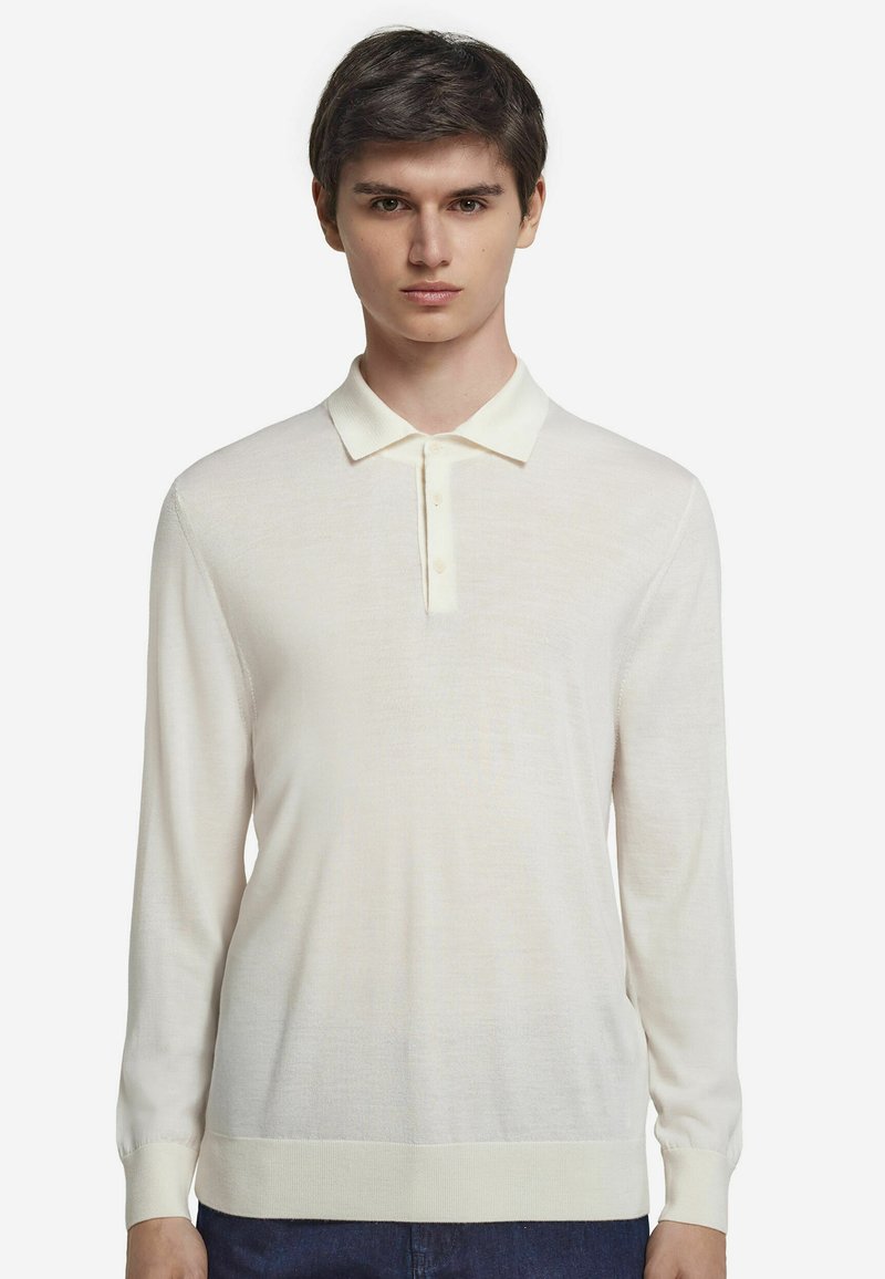 Ljuskrämfärgad långärmad pikétröja med treknapplås, ribbade ärmslut och ett mjukt, texturerat tyg.