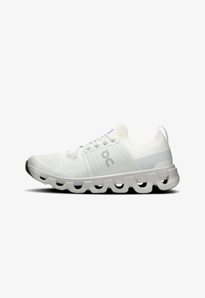 Chaussure de course athlétique blanche avec dessus en mesh respirant, semelle segmentée unique, et logo latéral sur fond blanc.