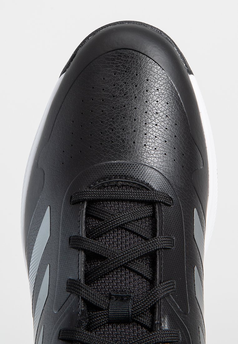 Baskets de sport noires avec un dessus en cuir texturé, des sections en mesh, des bandes d'accent gris et une semelle extérieure blanche. Présente un laçage traditionnel.