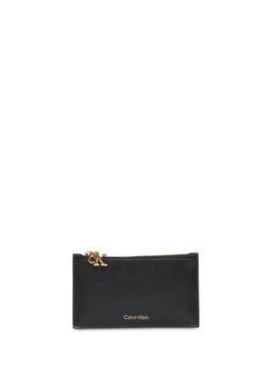 Pochette rectangulaire en cuir noir avec fermeture éclair dorée et logo Calvin Klein doré sur le devant, le curseur de la fermeture éclair comporte également les initiales CK.