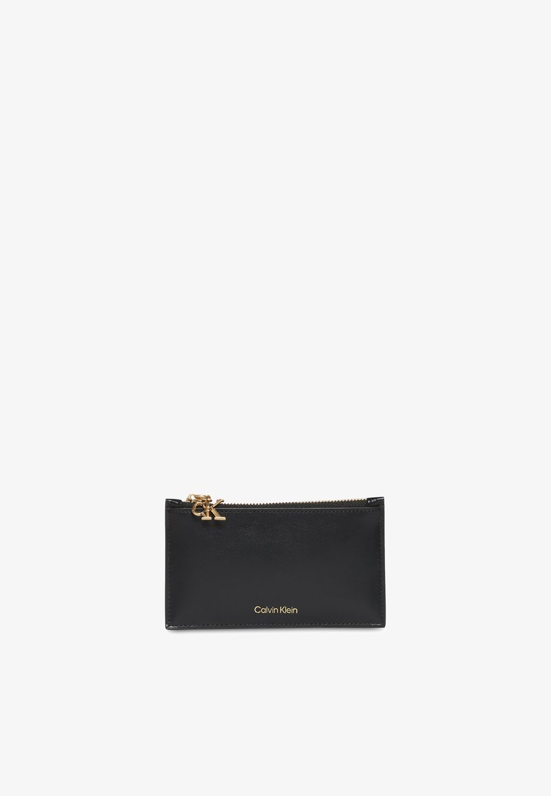 Pochette rectangulaire en cuir noir avec fermeture éclair dorée et logo Calvin Klein doré sur le devant, le curseur de la fermeture éclair comporte également les initiales CK.
