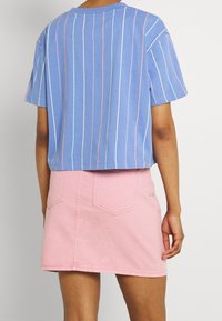 Blårandig t-shirt med korta ärmar, ihop med en rosa denim minikjol. T-shirten har tunna vertikala ränder och en kort design.