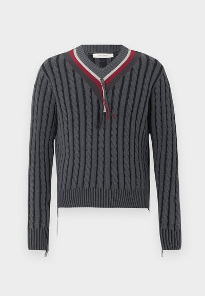 Pull en maille torsadée gris foncé avec poignets et ourlet côtelés, col en V avec rayures rouges, blanches et gris foncé, et détails effilochés.