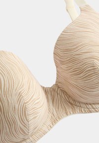 Sostén beige con patrón de ondas en crema y marrón claro. Tejido suave, copas acolchadas y tirantes ajustables. Diseño sin costuras con acabado liso.