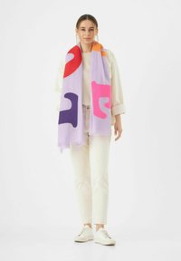 Écharpe violette avec des formes abstraites en rouge, rose et marine ; fabriquée en tissu doux, avec des bords frangés et un design léger.