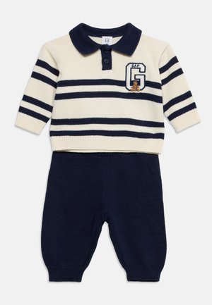 Gestrickter Babypullover mit creme- und marineblauen Streifen, Kragen, GAP-Logo und Teddybär-Design, kombiniert mit einfarbigen marineblauen Strickhosen.