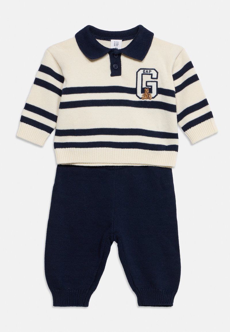 Pull bébé en maille rayée crème et bleu marine avec col, logo GAP et motif ours en peluche, associé à un pantalon en maille bleu marine uni.