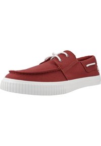Zapatilla de lona roja con perfil bajo, suela de goma blanca y puntera redonda. Presenta cordones blancos y un acento lateral cerca del talón.