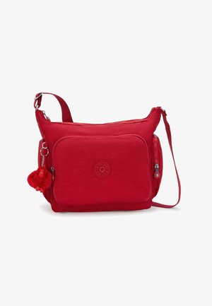 Sac d'épaule en tissu rouge avec une fermeture éclair, une poche avant et une sangle réglable. Comprend un porte-clés pompon et un logo en relief.