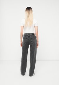 Høyt midt liv svarte jeans i løs passform, med fem-lomme design, synlige sømmer og en merkelapp bak.