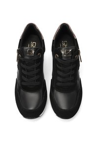 Sneaker nera con una combinazione di pelle liscia e camoscio. Presenta lacci, accessori in ottone dorato e una suola testurizzata.