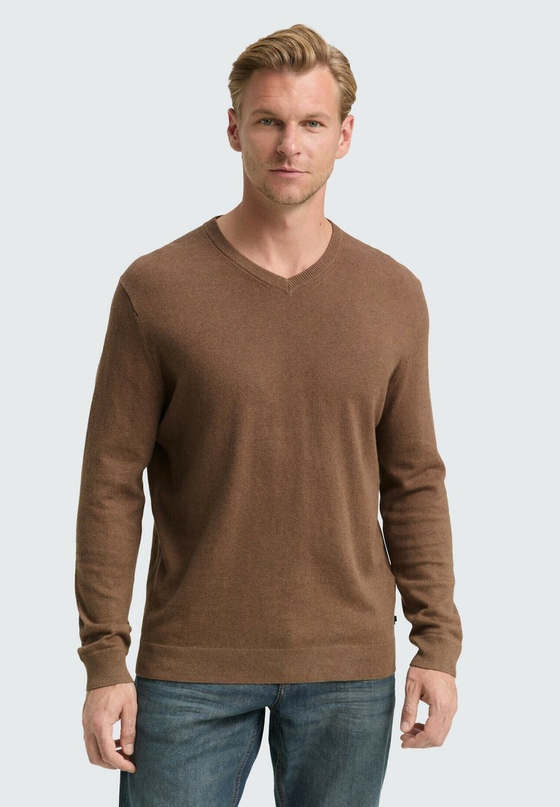 Brauner, langärmeliger V-Ausschnitt-Pullover mit weicher Textur. Mit gerippten Bündchen und Saum, über blauen Jeans getragen.