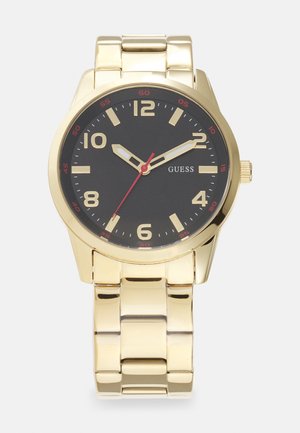 Montre-bracelet en métal doré avec un cadran noir. Caractéristiques de grands chiffres en or audacieux, une aiguille des secondes rouge et un bracelet brillant.
