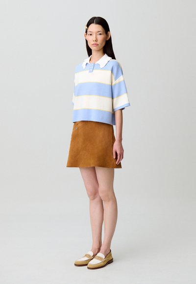Maglione corto a righe blu, bianco e giallo con colletto bianco, abbinato a una gonna a trapezio in camoscio marrone e mocassini beige.