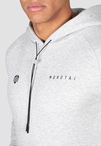 Light gray hoodie with a drawstring, featuring a black logo "MOROTAI" and a textured fabric. Close-up on the neckline and hood design.