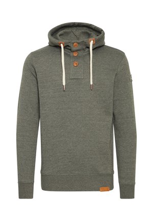 Kapucineritega pusa heledas tumerohelises kangas, millel on kolm puidust nööpi ja kreemivärvi paelad. Tootel on silt alumises paremas nurgas.