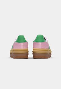 Multicolored sneakers featuring green suede heel, pink suede upper, white accents, and a stacked brown rubber sole with textured pattern.