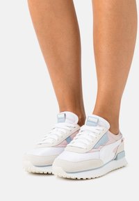 White and pastel pink athletic shoes with mesh and suede materials, a cushioned sole, and accents in light blue and red.