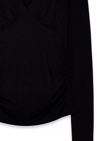 Top negro de manga larga con detalles fruncidos en el pecho y los lados, que presenta una silueta ajustada y un dobladillo curvado.