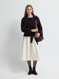 Peacoat blu navy in misto lana con cintura e ampi rever, abbinato a una gonna crema al ginocchio, scarpe marroni scure e una borsa a spalla marrone.