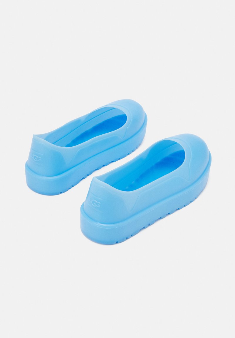 Niebieskie gumowe buty wsuwane z zaokrąglonym noskiem i wycięciami w górnej części. Posiadają teksturowaną podeszwę dla lepszej przyczepności. Gładkie, matowe wykończenie. Brak widocznych oznaczeń marki.