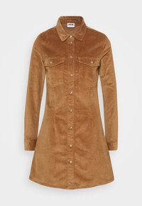 Brun kordfluwel skjortklänning med långa ärmar, två bröstfickor och knäppning fram. Texturerad tyg med utsvängd nederdel.